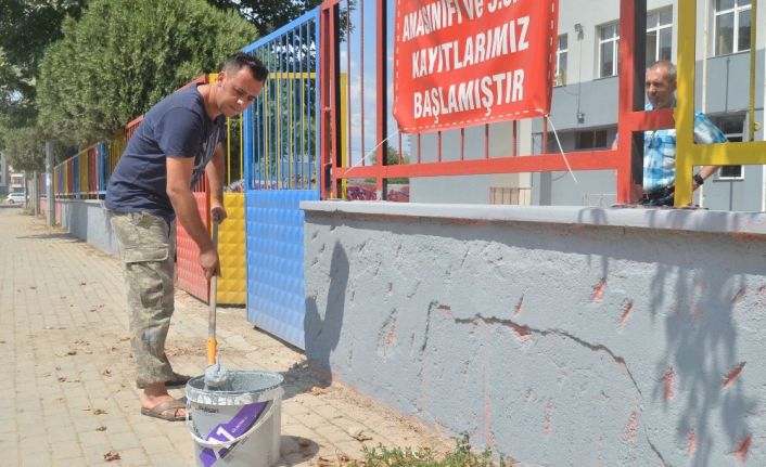 Okul müdürü elinde fırçayla okulu boyuyor